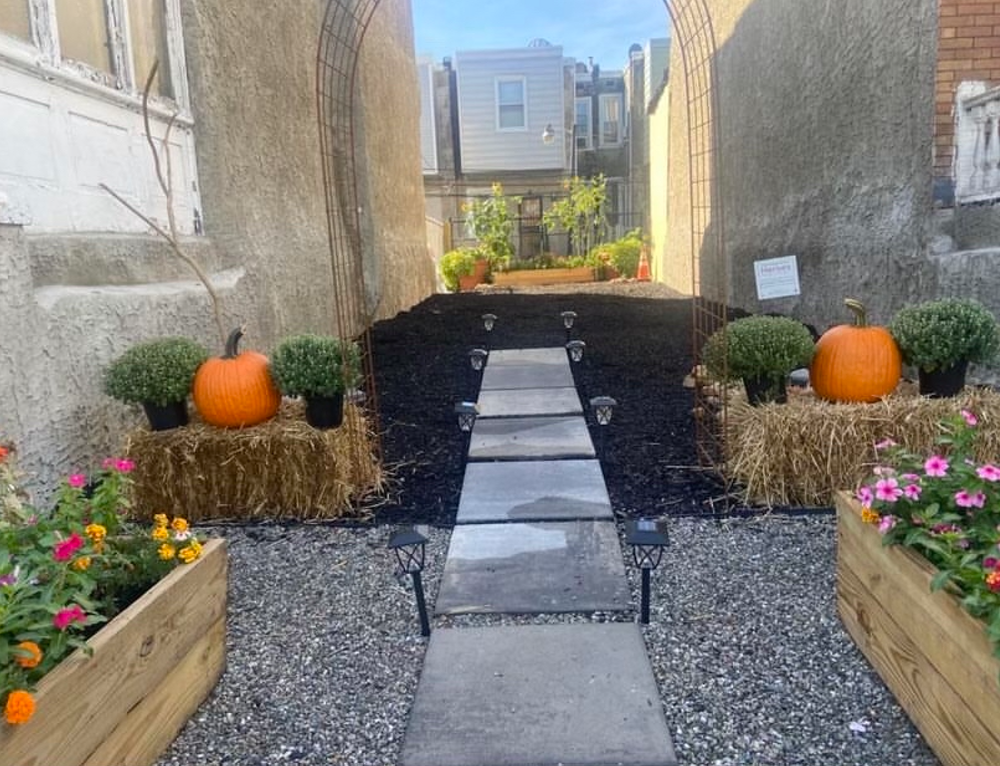 A garden with flower beds and pumpkins and a stone path down the middle